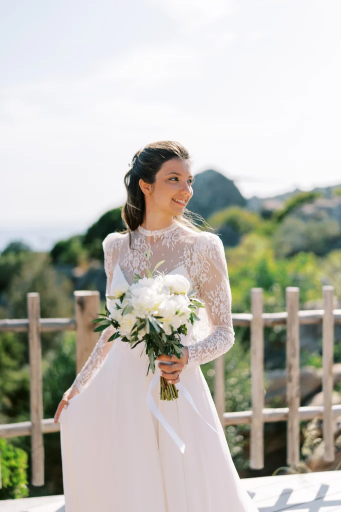 Braut auf Korsika vor der Trauung mit Blumenstraus und bick aufs Meer